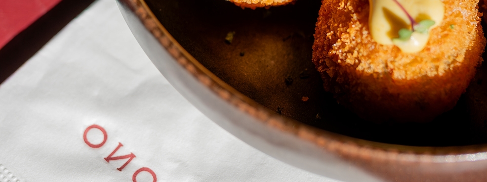 Golden croquette served on a dish, next to a white napkin.